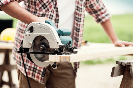 Close-up of carpenter cutting a wooden plank